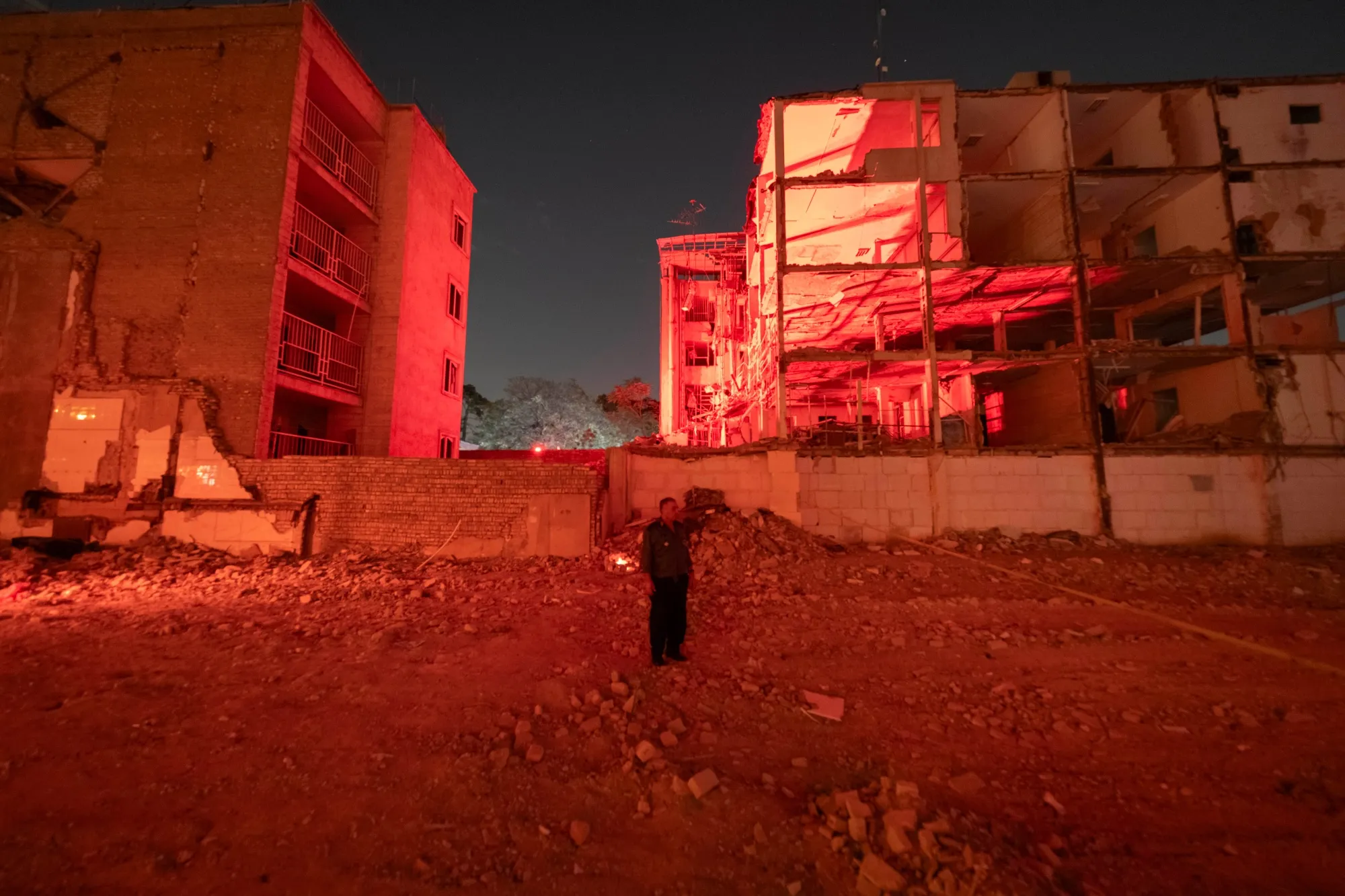 Damaged buildings illuminated in red light at night in Iran