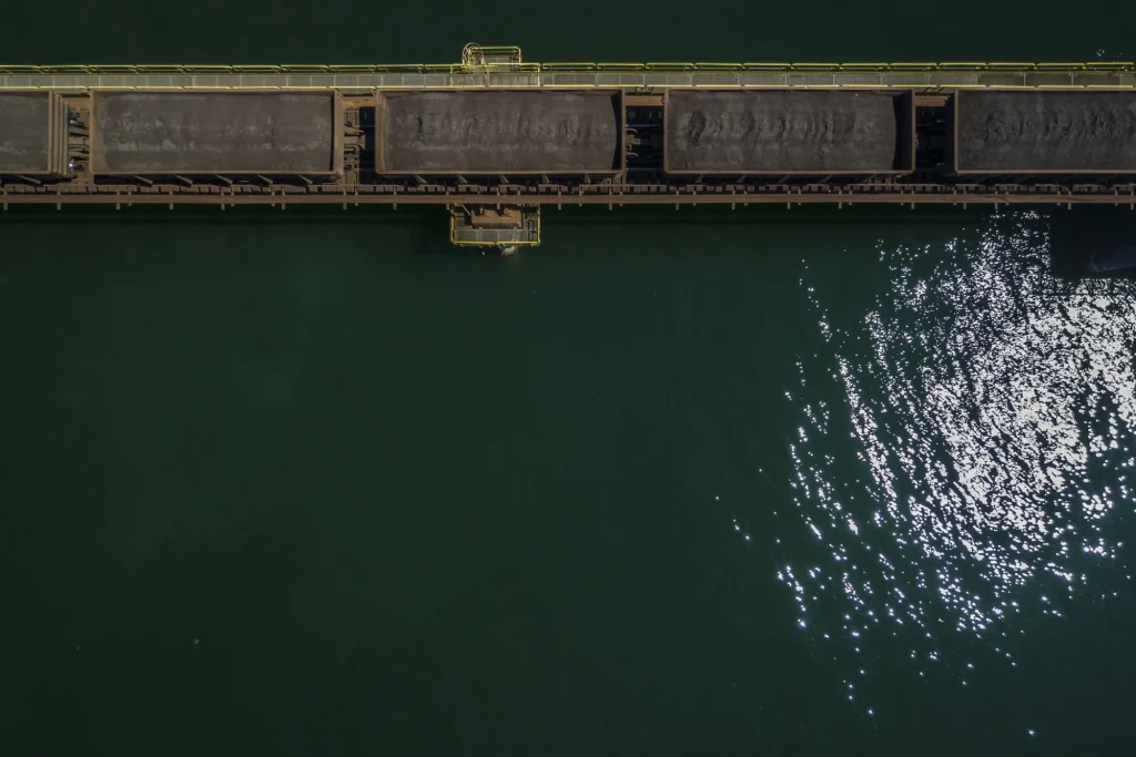 Aerial view of an iron ore loading port with rail cars beside the water
