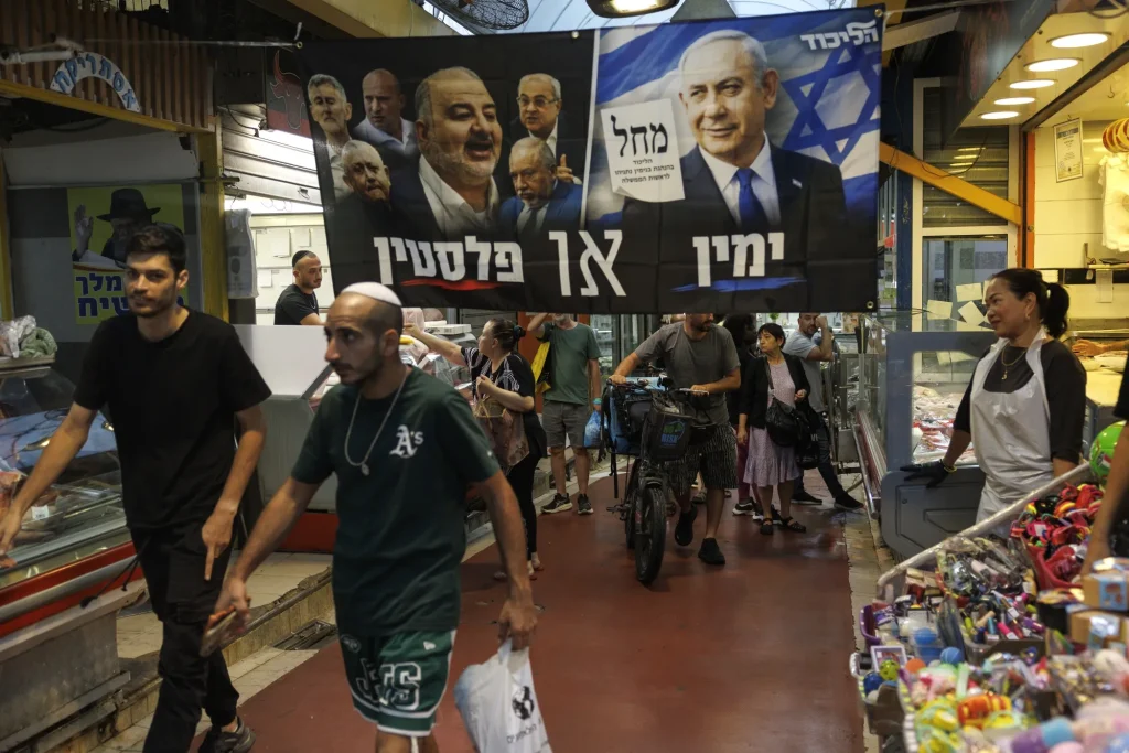 Shoppers walk through an Israeli market beneath political campaign banners